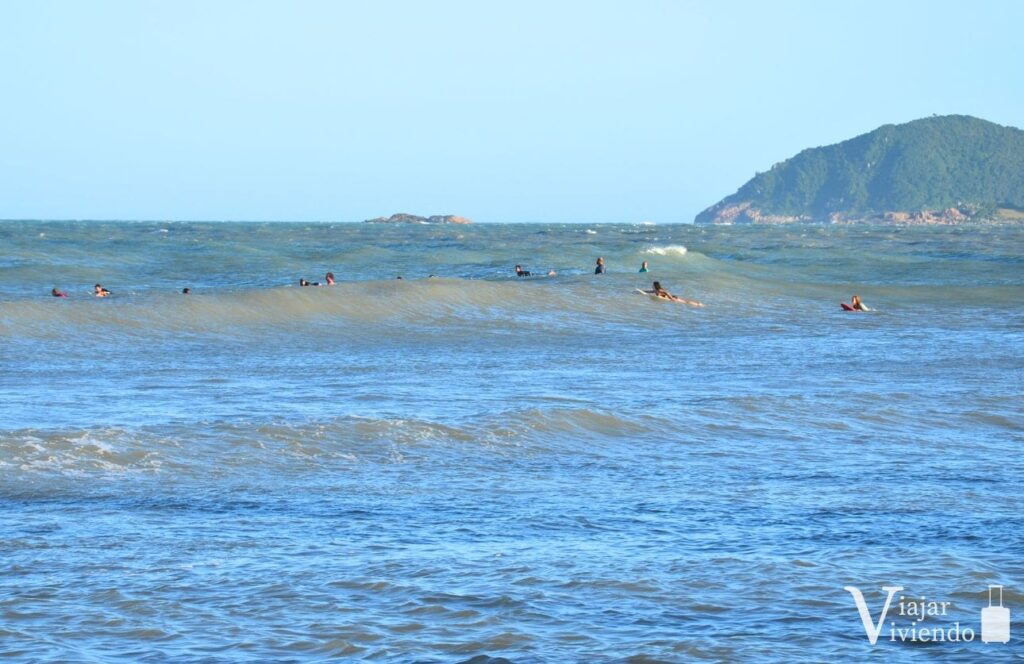 gente haciendo surf en la playa de ferrugem